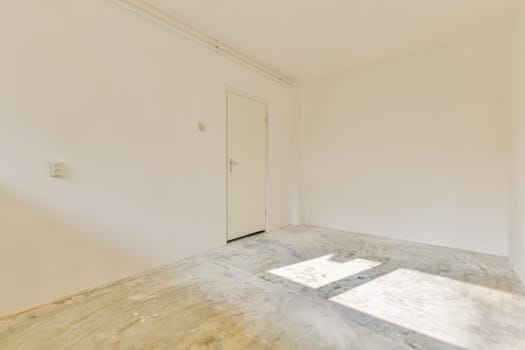 A bright and airy empty room featuring bare walls, a door, and sunlight casting shadows on the floor, creating a serene, minimalist space.