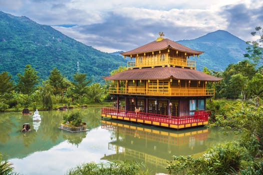 Landscape with Asian Buddhist Temple on water on the pond at the Vietnamese Nghia Son Pagoda in mountains in Nha Trang in Vietnam in Asia