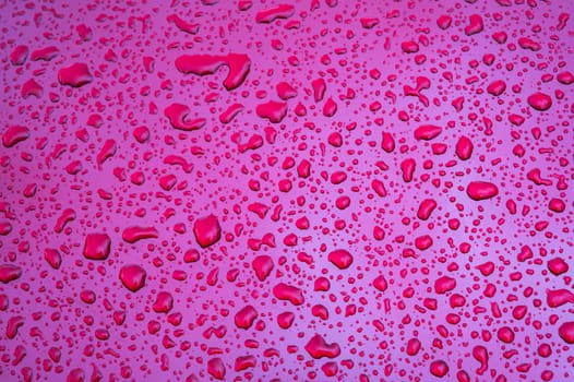 red background with texture of rain drops on purple metallic surface close up