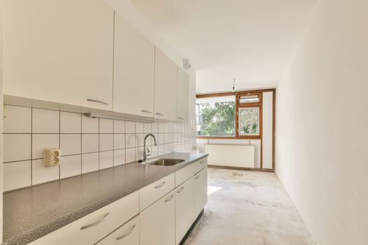 A minimalist kitchen featuring sleek cabinetry, a spacious countertop, and large windows allowing natural light to fill the room. The atmosphere is inviting and modern.