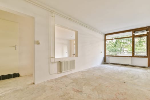 An empty, minimalist room featuring large windows that allow abundant natural light to flood in. The unfinished floor adds a sense of openness and potential.