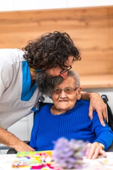 Male nurse showing affection to elderly woman by kissing her on the forehead in a nursing home, highlighting the importance of human connection in senior care