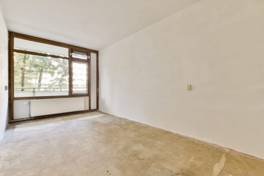 A bright, empty room featuring large windows that allow natural light to flood in, highlighting the simplicity of the space ready for decoration.