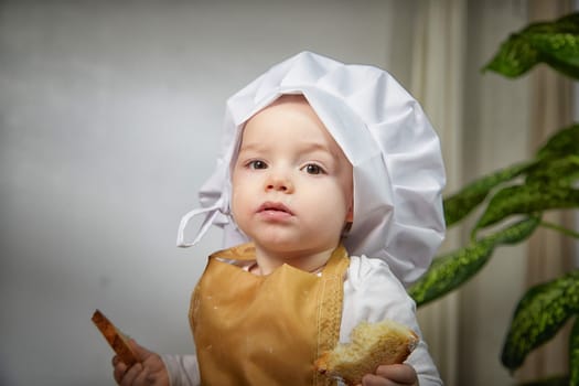 A curious boy wearing a chef's hat gazes thoughtfully while her photo is taken in a warm and inviting studio space.
