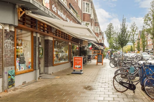A lively city street scene featuring a variety of shops, parked bicycles, and a beautiful sky. The architecture reflects a blend of modern and traditional design.