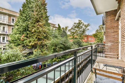 A beautifully designed balcony with a view of vibrant trees and plants, showcasing a tranquil urban setting. Perfect for relaxation and enjoying nature.