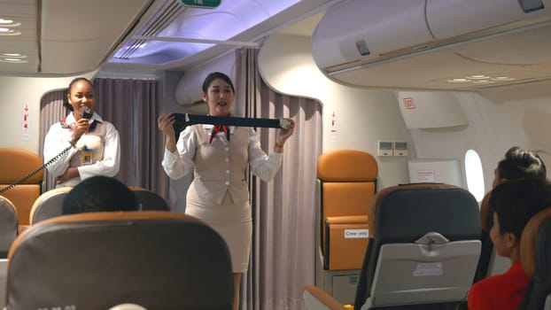 Asian stewardess safety explaining passengers how to use seat belt fastening in airplane, air hostess uniform safety demonstration presenting a seat belt, aircraft safety