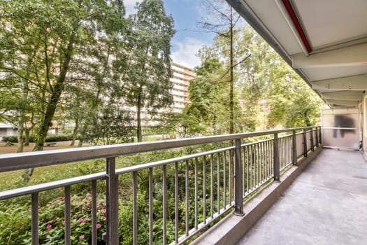 A well-maintained pathway through a modern urban park, flanked by greenery and residential buildings. The scene captures nature within an urban environment.