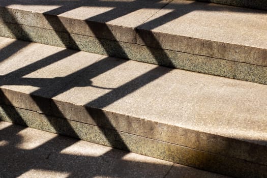 An artistic play of light and shadow dances across the concrete steps, effectively creating visual depth