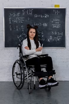 A determined student who uses a wheelchair is actively engaging with various math concepts displayed on a chalkboard
