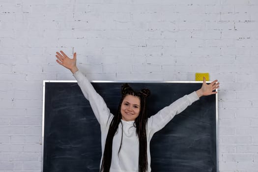 A joyful teacher celebrates in a classroom with arms raised, promoting an engaging learning environment.