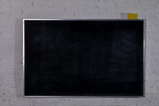 A perfectly clean blackboard affixed to a white brick wall, which is ideal for various educational or artistic projects