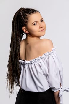 A stylish young woman poses elegantly, displaying her braided hair and trendy offshoulder top, radiating confidence
