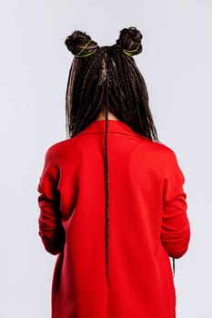 A stylish woman with braided hair and a vibrant red jacket poses confidently, showcasing a modern and trendy look