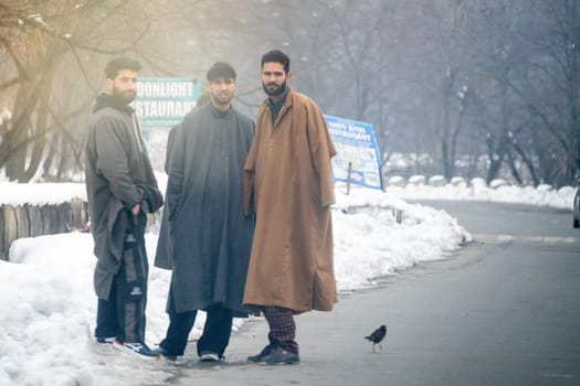 Srinagar, Kashmir - 4th Jan 2025: Young indian men walking along the side of the road looking at the oncoming traffic during sunrise in winters