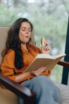 A young woman with long hair savoring a healthy sandwich, deeply engaged in reading a book The cozy environment, calm expressions, and natural light create a relaxing atmosphere