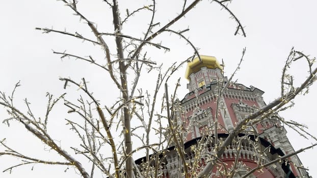 Christmas lights decorating bare tree branches in front of novodevichy convent bell tower in moscow, russia