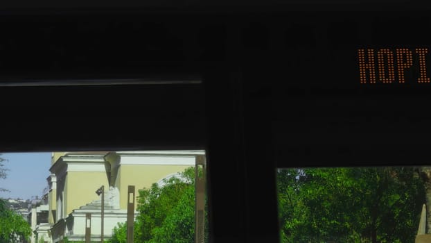 Passengers observing nice cityscape, including church and palm trees, through bus window