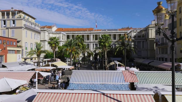 Cours saleya market, located in the heart of vieux nice, offers a vibrant atmosphere with colorful awnings, palm trees, and bustling shoppers
