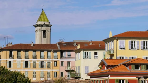 Traditional colorful buildings with a church tower under blue sky in nice, france