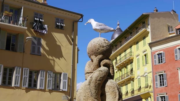 White seagull standing on a stone sphere of a fountain in a square of nice, france