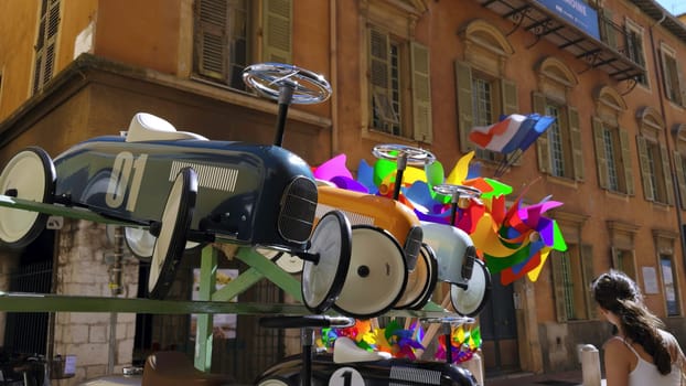 Toy cars and colorful pinwheels decorate a street in a french city