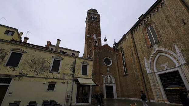 People walking around campo san barnaba in venice, italy, near a church and old buildings