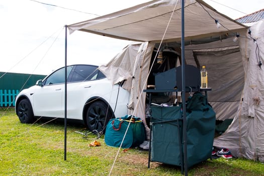 Car camping setup with tent and equipment in outdoor setting.