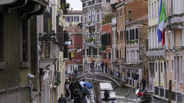 Venice, Italy - July, 2024:Tourists walking near a canal in venice, italy with gondolas navigating