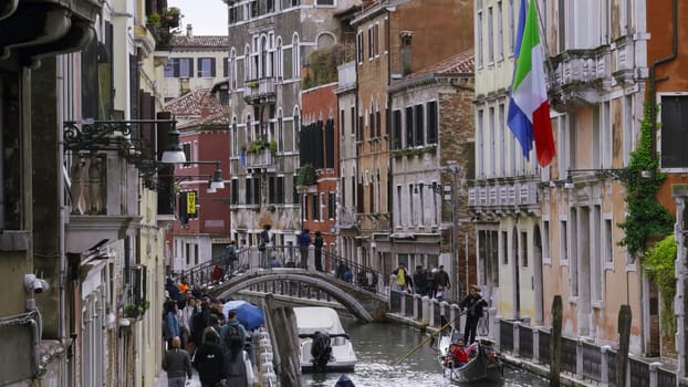 Venice, Italy - July, 2024:Tourists walking near a canal in venice, italy with gondolas navigating