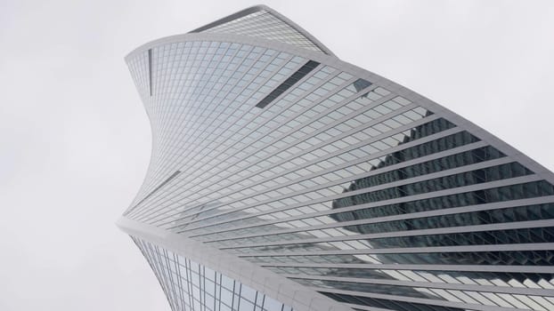 A stunning low angle view highlights a modern skyscraper, showcasing its innovative design and unique structure. Action