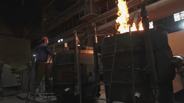 An industrial scene showcasing metalworking processes with intense flames erupting from the furnaces. Stock Clip