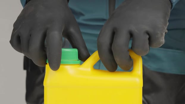 A figure in black gloves pours bleach into a yellow container, hinting at danger. He later hides a yellow bottle with a green cap, raising concern. Creative