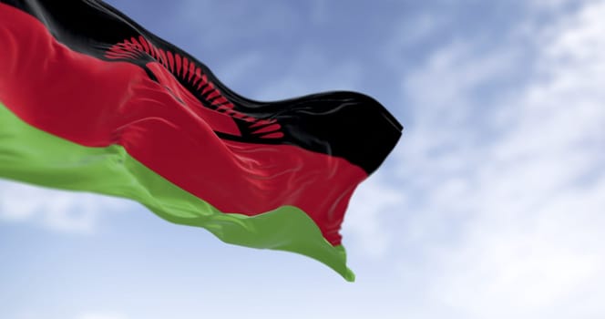 Realistic close-up of the Malawi flag featuring the rising sun, fluttering in the wind under a blue sky, symbolizing national pride, freedom, and unity. 3D fabric texture illustration.