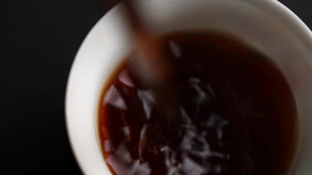 A closeup shot capturing the warmth and comfort of hot tea being skillfully poured into a beautiful cup. Media