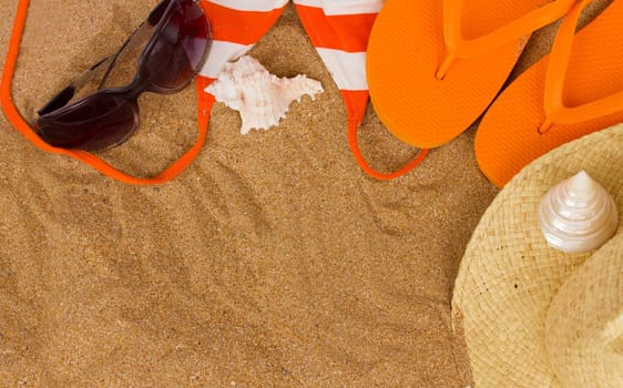orange sandals  and sunbathing accessories at sand with copy space