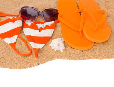 orange sandals and swimming siut on sand  isolated on white background