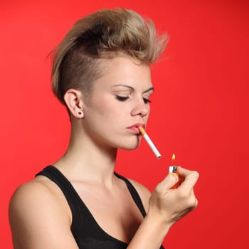 Fashion woman lighting a cigarette with a red background