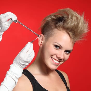 Professional hands making a piercing hole to a fashion woman on a red background