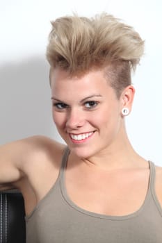 Portrait of a fashion teenager girl with punk style sitting on a couch