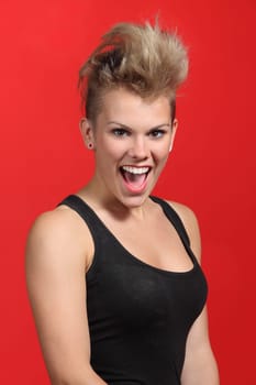 Portrait of a fashion punk hair style woman excited on a red background