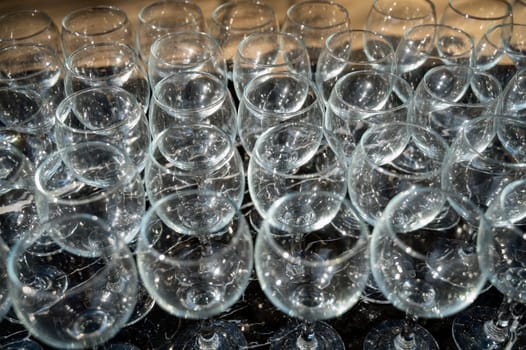 Many empty clean wine glasses on dark background in daylight. wine glasses, bar, glass, rows, empty glass. Wine glasses on black background close-up.