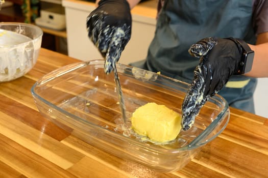 Close up of hands shaping fresh homemade butter in a glass dish.