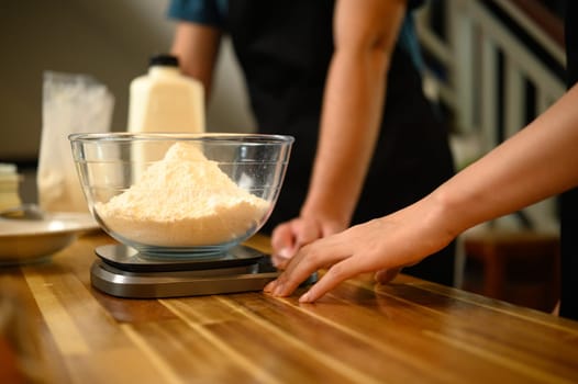Close up of couple measuring flour for homemade pancakes in a cozy kitchen.