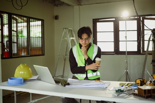 Engineer reviewing construction plans on a laptop at a job site.