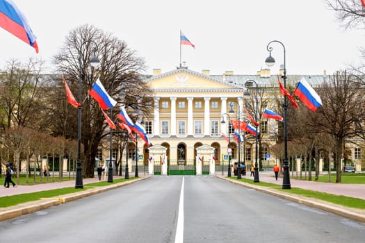 Saint-Petersburg, Russia - 05.05.2024. The historic building of the Smolny Institute with Russian flags hung in a prominent place along the alley.