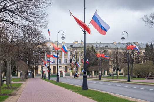 Saint-Petersburg, Russia - 05.05.2024. The historic building of the Smolny Institute with Russian flags hung in a prominent place along the alley.