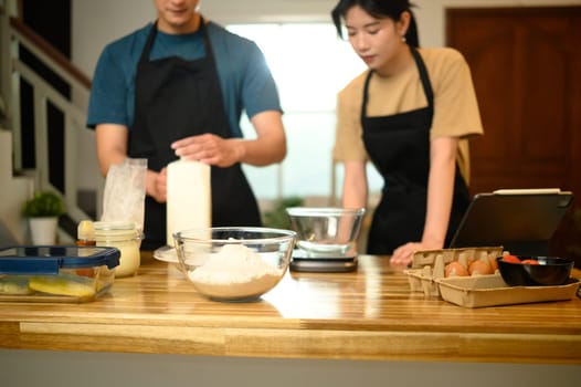 Young couple preparing pancake batter together in a cozy kitchen.