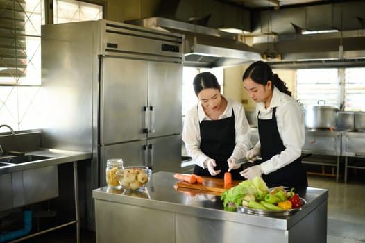 Female student learning to cut vegetables during a hands on culinary class.