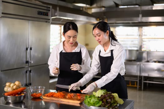 Female student learning to cut vegetables during a hands on culinary class.